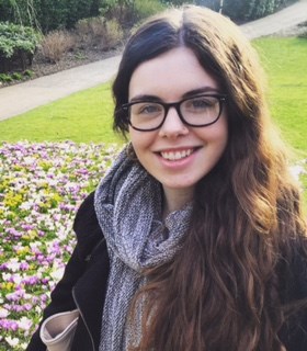 Close up photo of Joanna with greenery in the background.