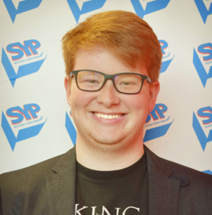 A close up photo of John with Scottish Youth Parliament banner logos in the background.