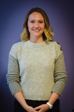 Photo of Laura with a purple background.