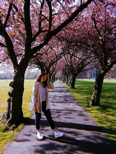 Photo of Martina standing in a park with blossom trees in the background.