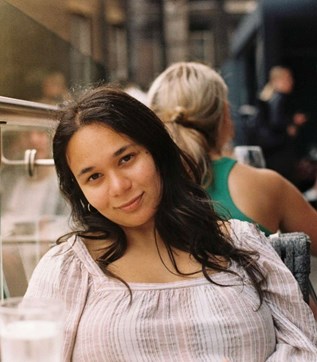 Photo of Ambareen sitting with a person in the background.