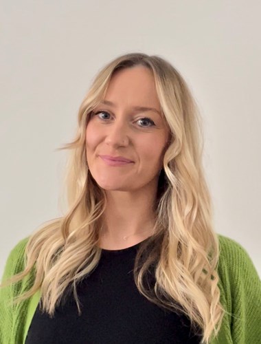 Photo of Carly, Assistant Director, wearing green cardigan. White background.